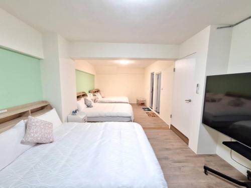 a room with two beds and a flat screen tv at 宜蘭花境民宿 in Wujie