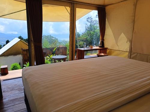 een groot bed in een kamer met een groot raam bij Mountview Bali in Kubupenlokan