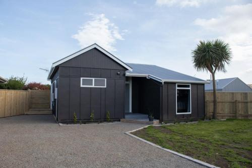 a black garage with a palm tree in a yard at The Window Seat - pet-friendly 1BR apartment in Waitara