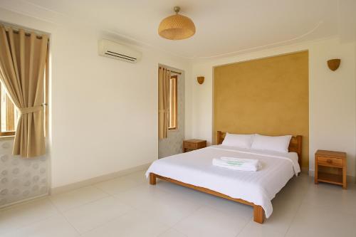 a bedroom with a white bed and a window at Coconut Garden Mui Ne in Mui Ne