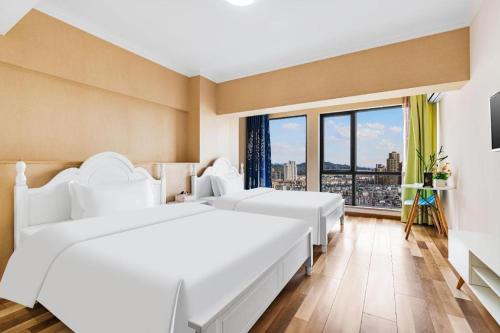 2 witte bedden in een kamer met een groot raam bij Kunming Tong Yi Business Hotel in Kunming