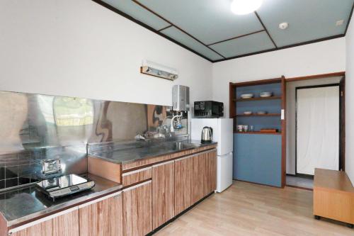 a large kitchen with wooden cabinets and a refrigerator at ひだまりの宿 まゆしょう in Omachi