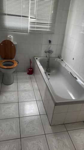 a bathroom with a toilet and a bath tub with a toilet seat at Goshen in Johannesburg