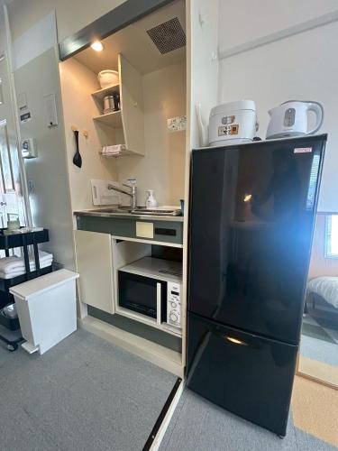 a kitchen with a black refrigerator with a microwave at Cube Court 瀬田203 in Otsu