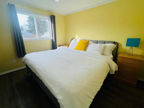 a bedroom with a large bed with yellow walls and a window at Cozy 2-Bedroom Home in Hinton in Hinton