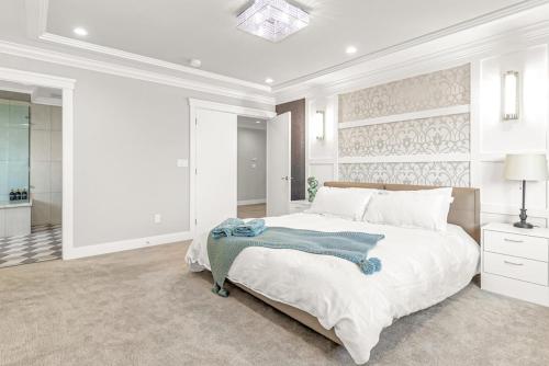 a white bedroom with a large bed and a bathroom at 8BR New Spacious Home White Rock HVAC Free Parking in Surrey