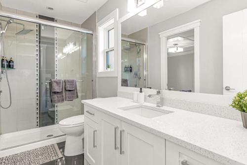 a white bathroom with a sink and a shower at 8BR New Spacious Home White Rock HVAC Free Parking in Surrey