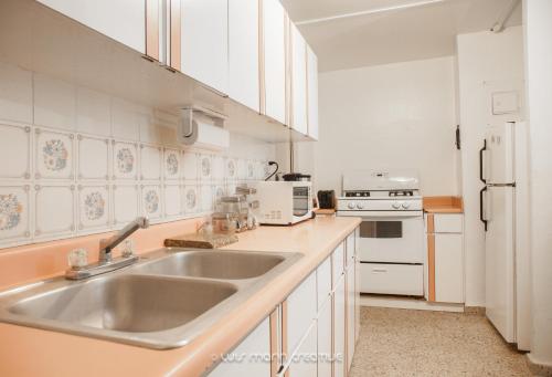 cocina con fregadero y nevera blanca en Safe Quiet Apartments Near Airport, en Carolina