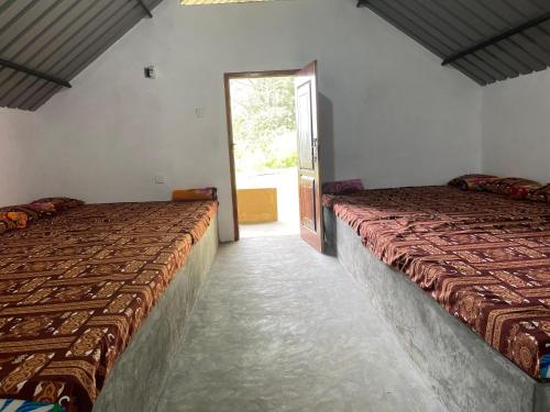 een kamer met 2 bedden in een kamer met een raam bij Royal Mountain Edge ,Knuckles in Rangala