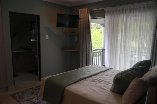 a bedroom with a bed and a large window at GuestHouseVine&Stone in Clarens