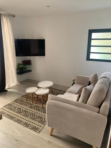 Una sala de estar con un sofá y dos mesas. en L horizon, en Ravine des Cabris