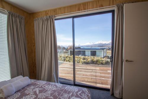 a bedroom with a bed and a large sliding glass door at Nordic Escape - Lake Tekapo in Lake Tekapo
