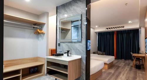 een badkamer met een wastafel en een slaapkamer met een bed bij Borrman Hotel Jiangyin Zhouzhuang in Xiwujieqiao