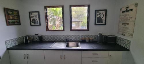 a kitchen counter with a sink and two windows at Polly's Retreat in Coffin Bay