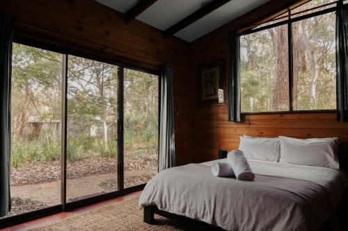 a bedroom with a bed and large windows at Bimbi Forest Eco Lodge - Denmark in Denmark