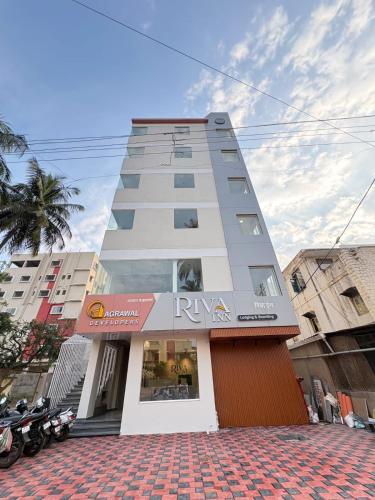 a tall building with a riya sign in front of it at Hotel Riva Inn in Miraj