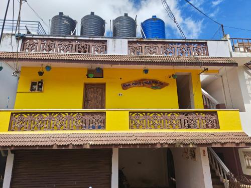 a yellow building with a balcony with buckets on top at kMT ooty villa mangal niketen in Ooty