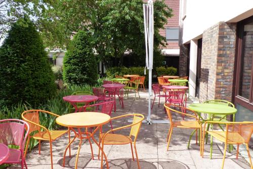 een groep tafels en stoelen op een terras bij The Originals City, Hôtel Castel Burgond, Dijon Ouest in Daix