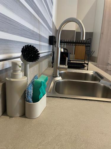a kitchen sink with a brush in a container next to it at Cantonments One Bedroom Deluxe in Accra