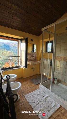 a bathroom with two toilets and a shower and a window at The quiet yellow house in Pornassio