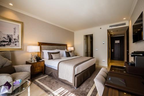 a hotel room with a bed and a living room at Herbert Samuel Jerusalem in Jerusalem