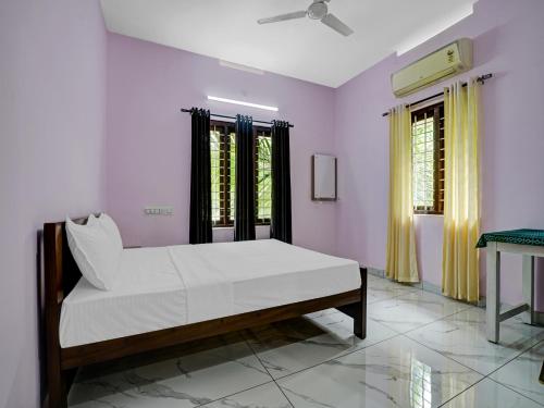 Un dormitorio con una cama con sábanas blancas y una ventana. en Shalom Palace Residency, en Neriyamangalam