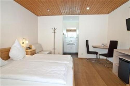 a white room with a bed and a table and chairs at Hotel-Gasthof Zur Linde in Neukirchen beim Heiligen Blut