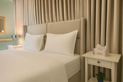 a bed with white sheets and pillows in a room at شقة واسعة وأنيقة ثلاث غرف نوم in Al Khobar