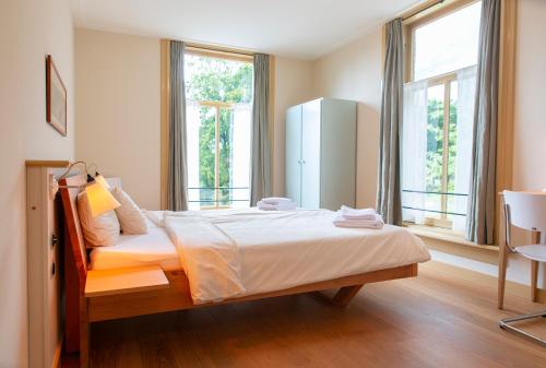 ルーネンにあるDen Eikenboomのベッドルーム1室(大型ベッド1台、窓2つ付)