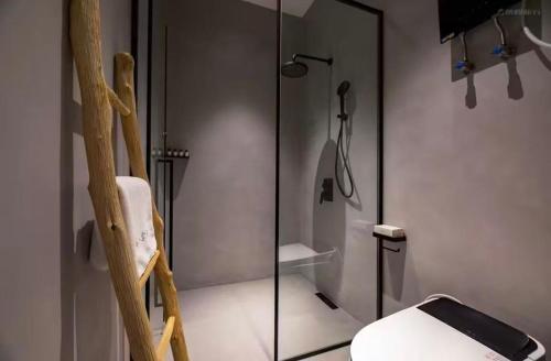 a bathroom with a glass shower with a phone on a chair at Huangshan Xishui Yunjian Forest Resort Hotel in Huangshan