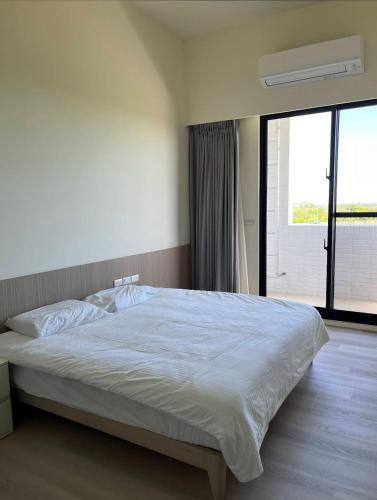 a bedroom with a white bed with a large window at Miruku in Taitung City