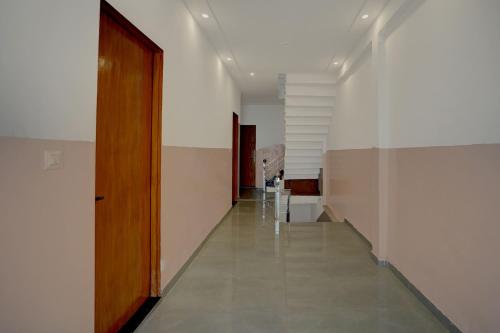 a hallway with a wooden door and a hallway with stairs at Hotel O RJ HOTEL INN in Pānchgaon