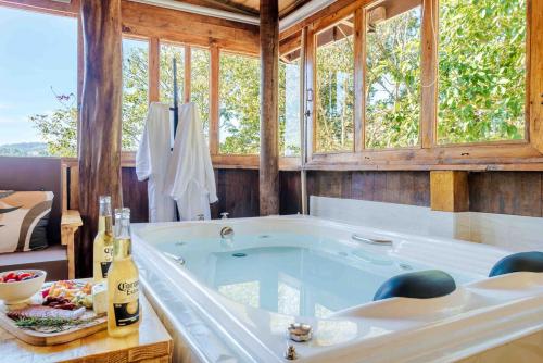 eine große Badewanne in einem Raum mit Fenstern in der Unterkunft Chalé romântico com banheira aquecida in Nazaré Paulista