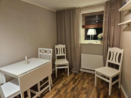 a dining room with white chairs and a table and a window at Liten lägenhet i Smedby, Norrköping in Norrköping