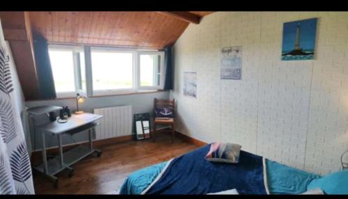 AudervilleにあるChambre phareのベッドと机と窓のある寝室