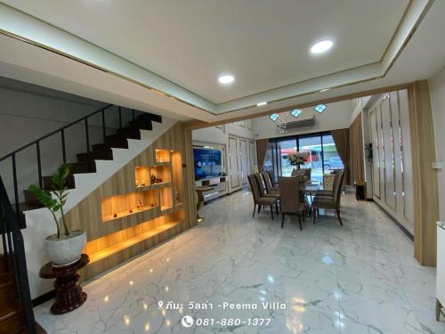 a dining room with a table and chairs and a staircase at Peema Villa ภีมะ วิลล่า in U Thong