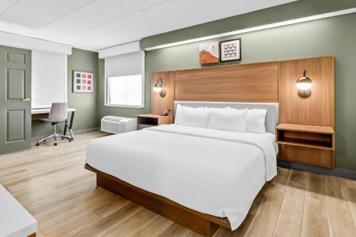 a bedroom with a large white bed and a desk at Spark by Hilton Lynchburg in Lynchburg