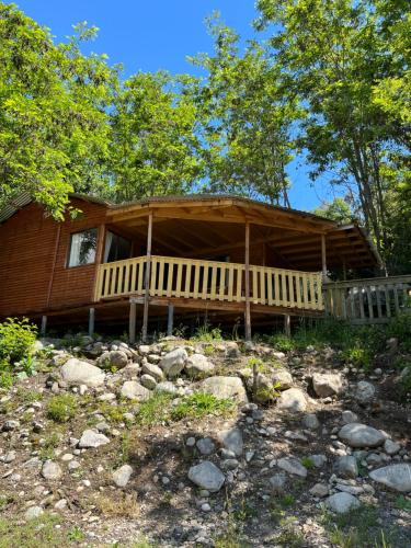 a log cabin with a large porch in the woods at Ancoa Lodge in Linares