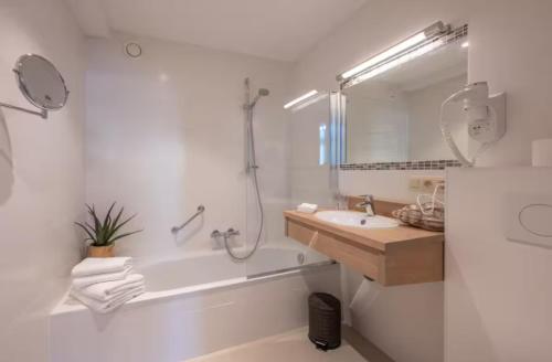 een badkamer met een bad, een wastafel en een spiegel bij Gastenkamer BLOOM in Brugge