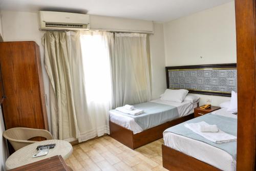 Una habitación de hotel con dos camas y una ventana. en Lorenda hotel, en El Cairo