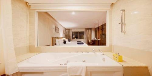 a bathroom with a large bath tub with a mirror at Sandals Stay Hotel in Da Nang