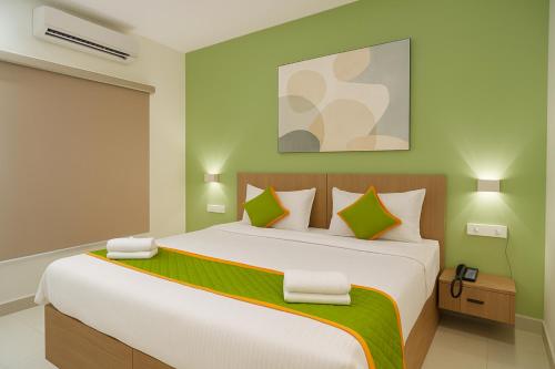 een slaapkamer met een groot bed met groene muren bij Elegant Residency in Coimbatore