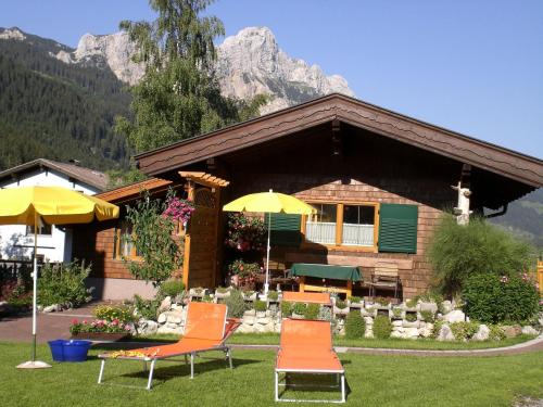 a house with chairs and umbrellas in front of it at Almdorf Tirol in Haldensee