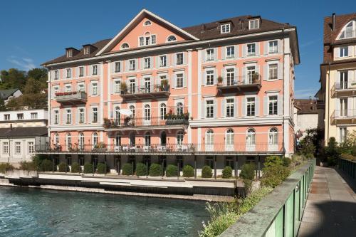 a large pink building next to a river at Limmathof Baden - Historisches Haus & Spa in Baden
