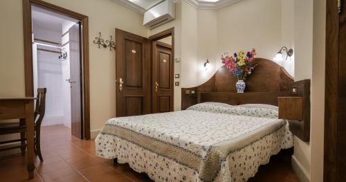a bedroom with a bed and a vase of flowers at Hotel 4 Coronati in Rome
