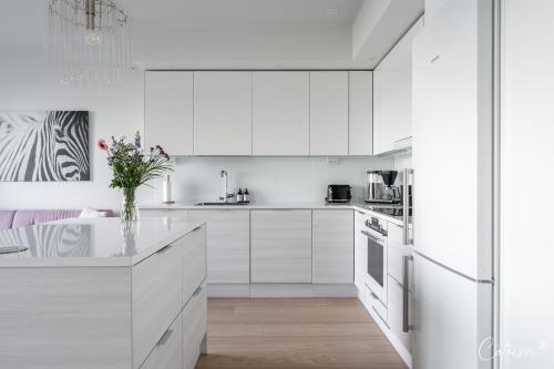 a white kitchen with white cabinets and a vase of flowers at New apartment with sauna, lake and beach in Tampere