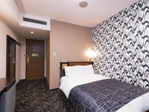 a hotel room with a bed and a wall at APA Hotel Kitakami Ekinishi in Kitakami