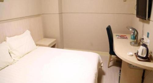 a hotel room with a bed and a desk with a telephone at Jinjiang Inn Wuxi Li Lake Yauntouzhu Scenic Spot in Wuxi