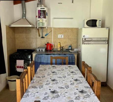 a kitchen with a table and a white refrigerator at Alojamientos en Cosquín in Cosquín