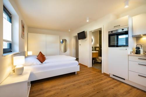 a bedroom with a white bed and a kitchen at S Apartment in Flachau